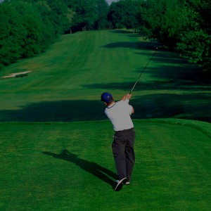 Golfer swinging on course