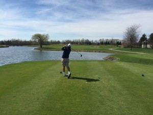 Young man hitting off of tee over water